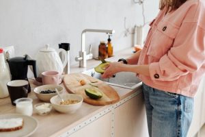 pexels photo 4151994 4151994 Woman in a pink shirt preparing a healthy avocado breakfast in a modern kitchen setting.
