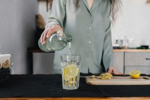 pexels photo 6933132 6933132 Woman pours water for lemon ginger infusion, promoting health and hydration.